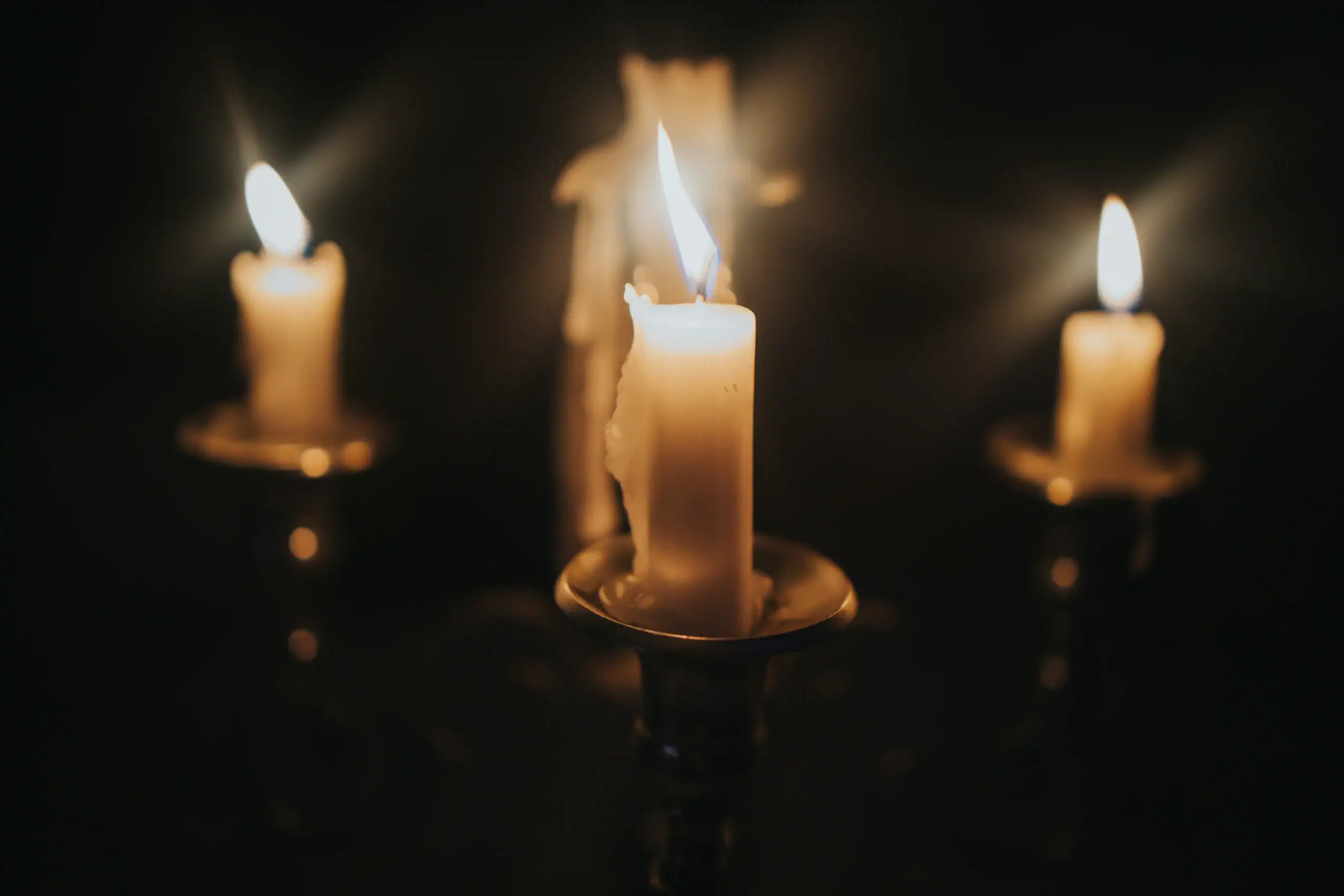Three softly glowing candles in elegant holders evoke the peacefulness of Islamic Funeral Services New York.