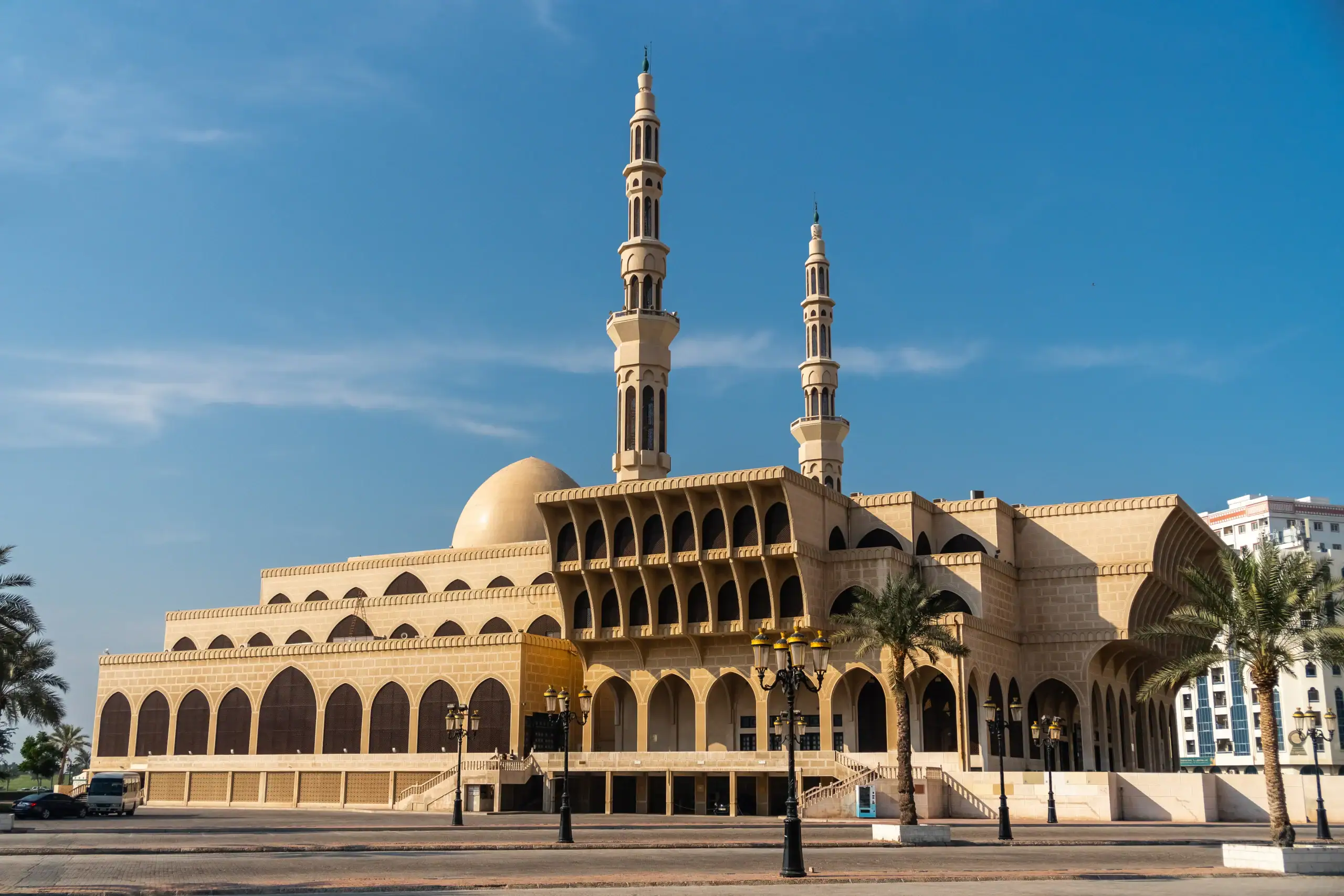 Large beige mosque with two tall minarets under a clear blue sky, ideal for Islamic Funeral Services New York.