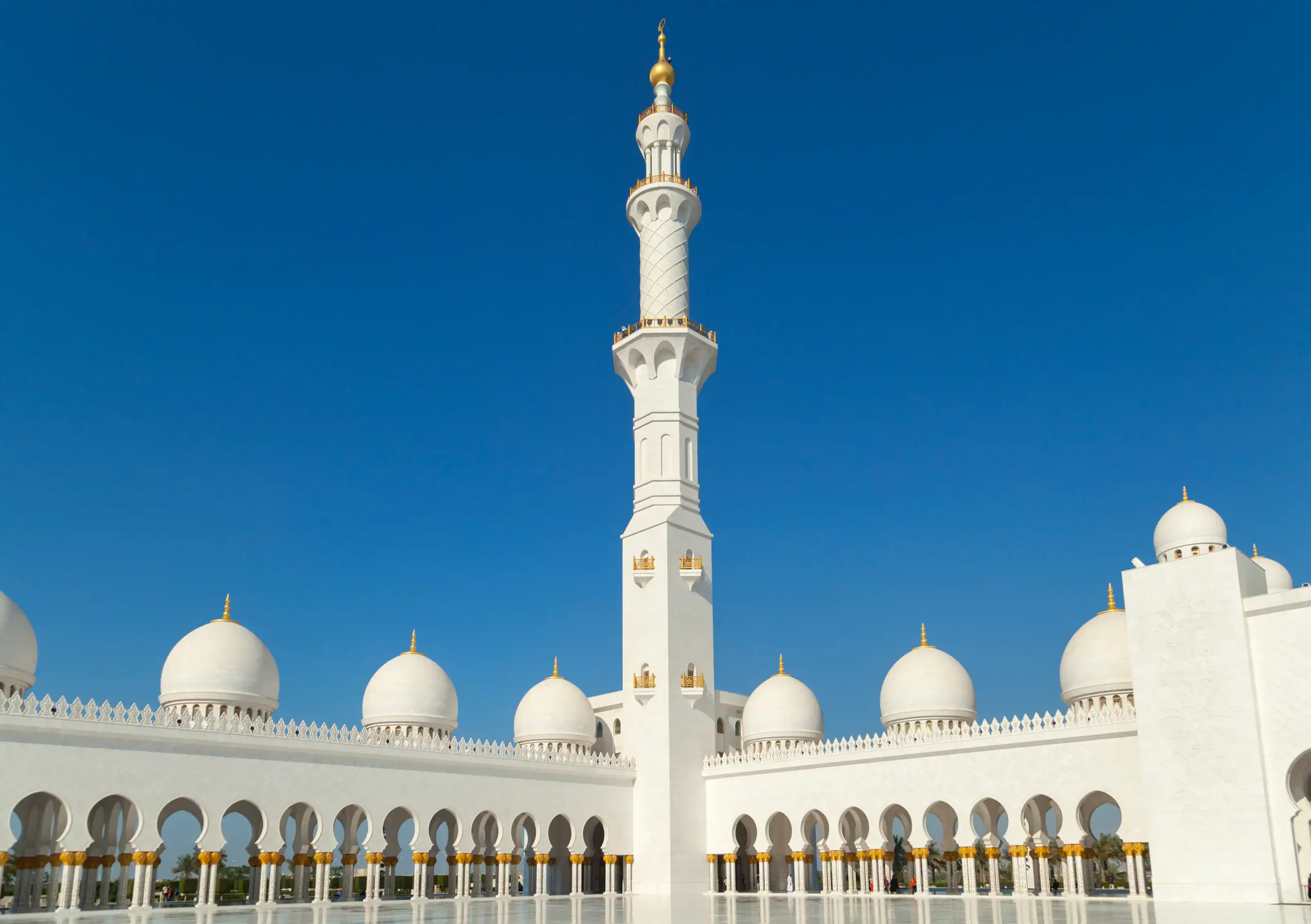 A white mosque with domes and a tall central minaret, featuring Islamic Funeral Services New York signage.